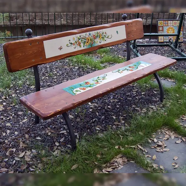 Wooden garden bench with hand-decorated lava stone insert.