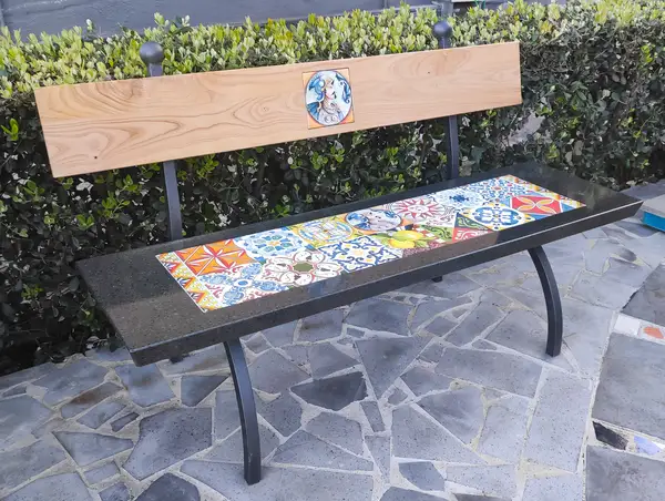 Garden bench with hand-decorated lava stone seat and wooden backrest.