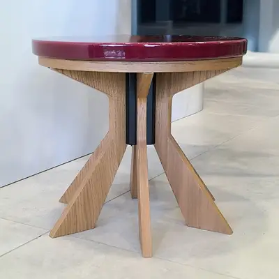 Round side table with a thick burgundy lava stone top and a sculpted wooden base