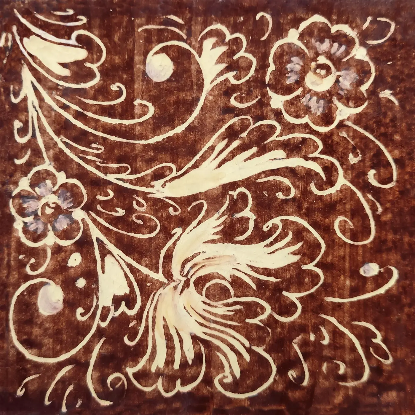 Decorated tile with white flowers, leaves and fine scrolls on a brown background