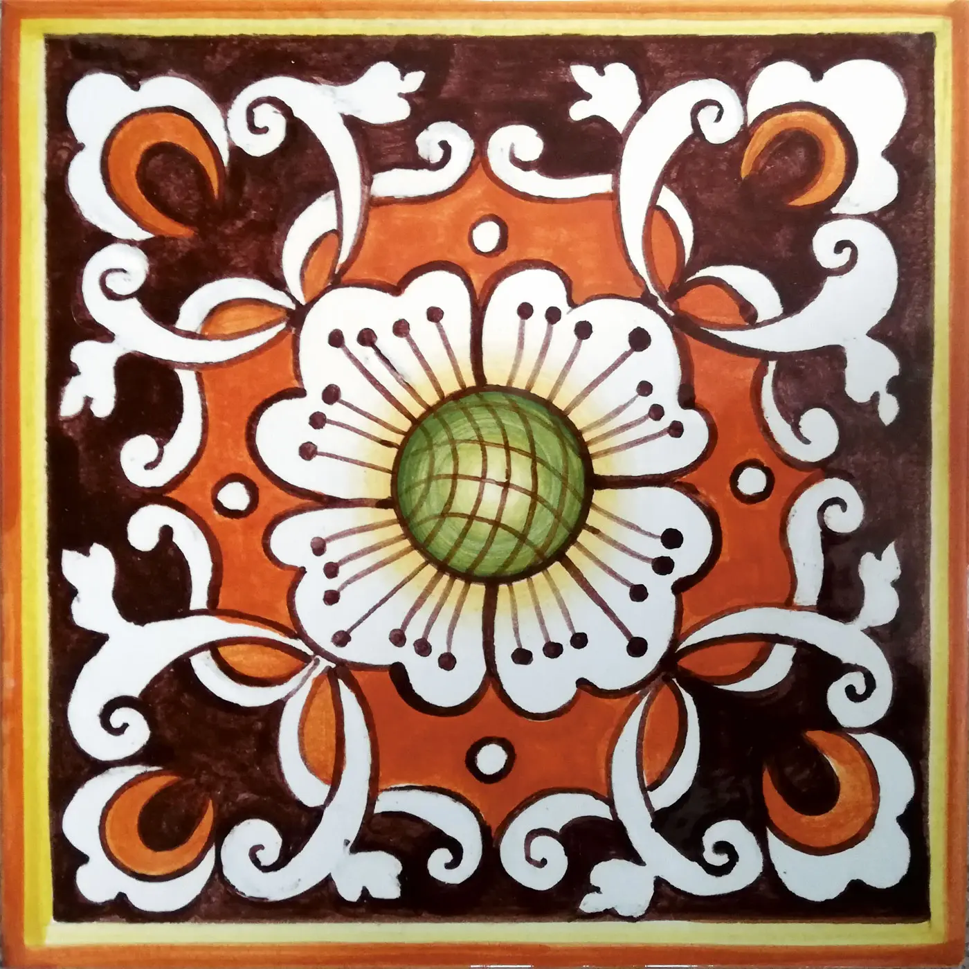 Decorated tile with a white flower with a green centre, white scrolls and orange shapes on brown with an ochre border