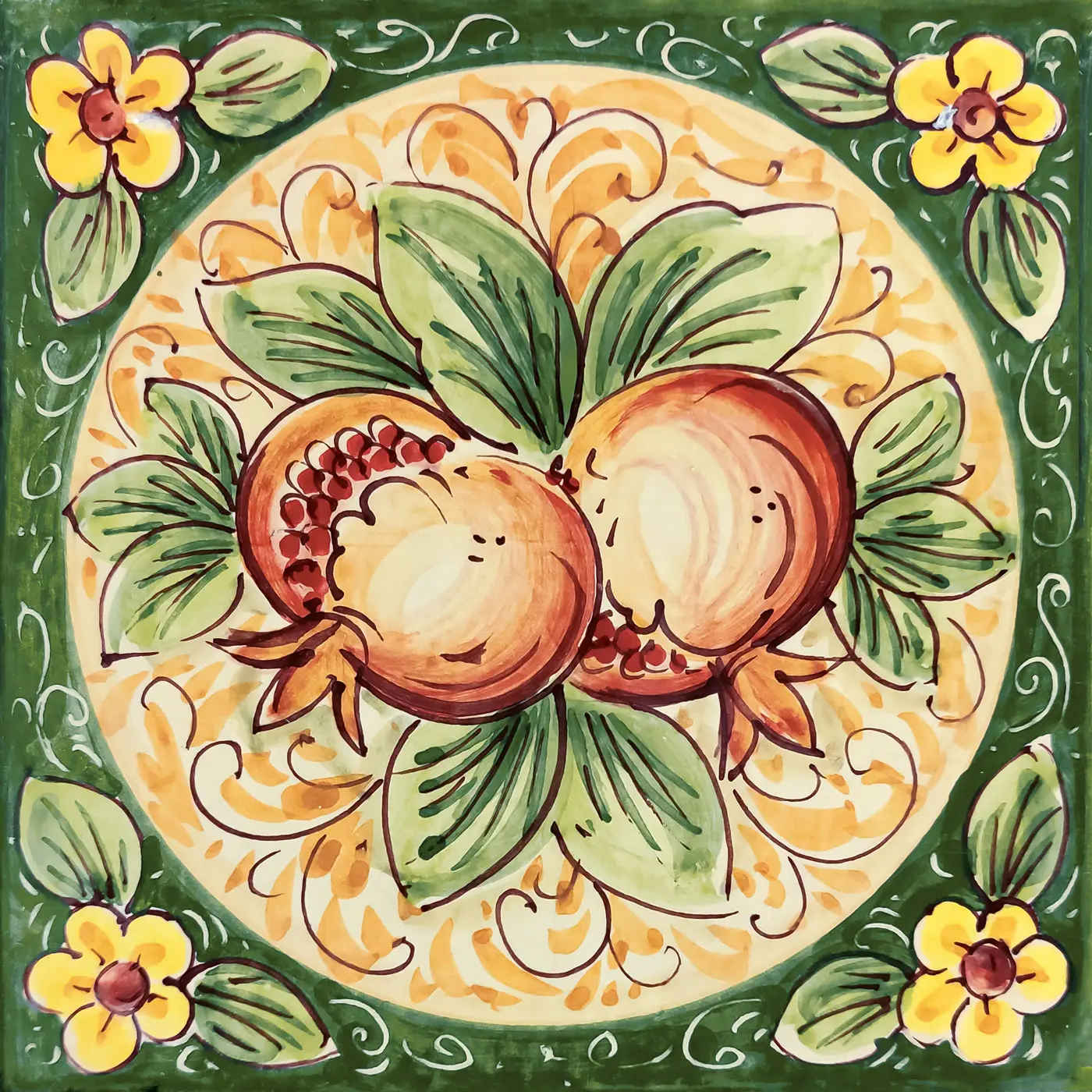 Decorated tile with two pomegranates and green leaves in an ochre medallion, with a green frame and small yellow corner flowers