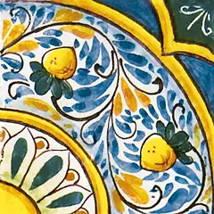 Fliese mit gelben Zitronen, Blättern und kleinen blauen Motiven entlang geschwungener Bänder mit gelben Konturen sowie blauen und grünen Flächen