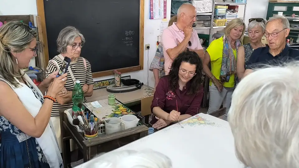 Eine Vorführung der Handdekoration in der Artesole-Werkstatt. Eine Kunsthandwerkerin bemalt eine Oberfläche vor der Besuchergruppe