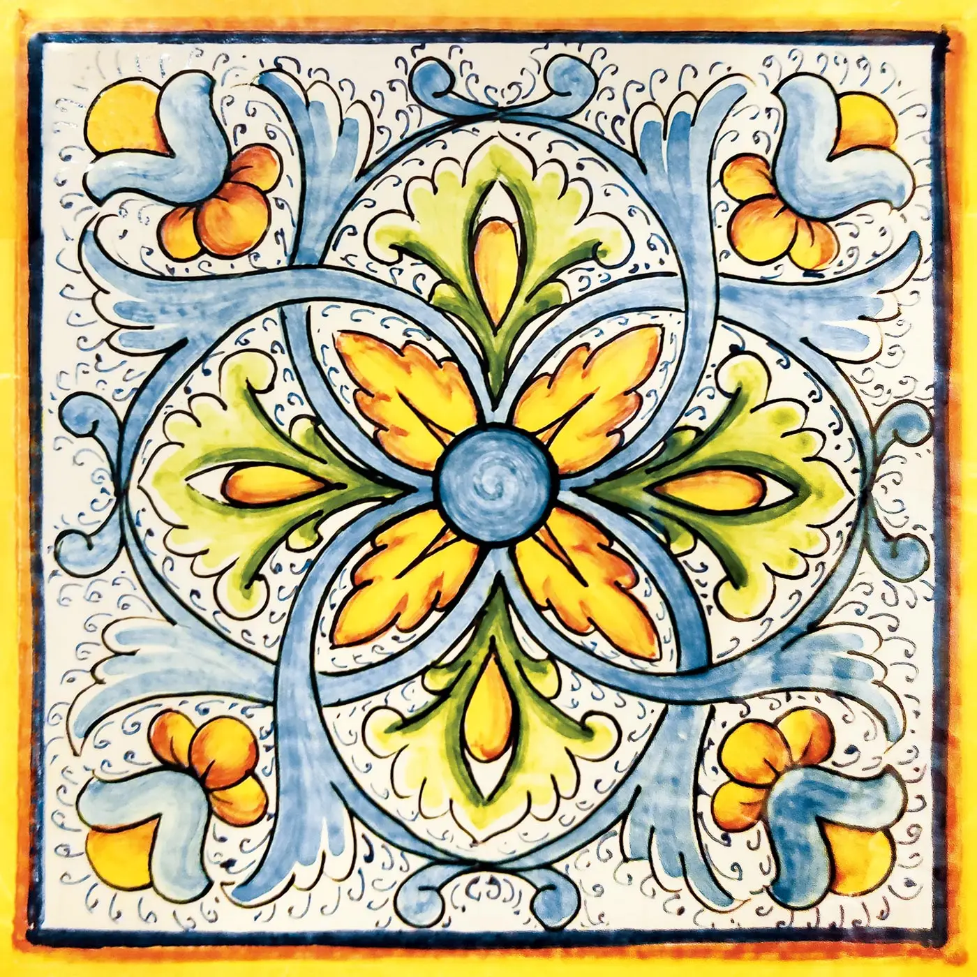 Azulejo decorado con una flor central azul con pétalos amarillos y verdes, volutas celestes y borde amarillo sobre fondo claro