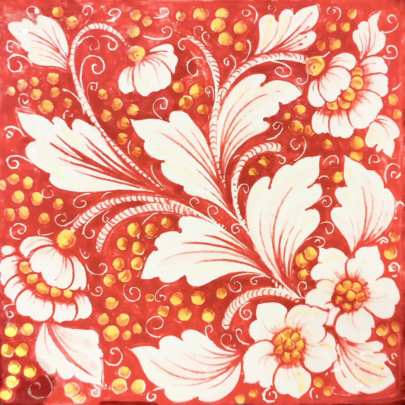 Azulejo decorado con flores y hojas blancas, volutas finas y pequeños puntos amarillos sobre fondo rojo