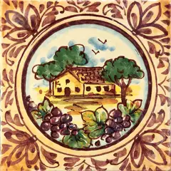 Azulejo decorado con una casa rural entre árboles en un medallón circular, racimos de uvas en primer plano y ornamentos color ciruela sobre fondo crema