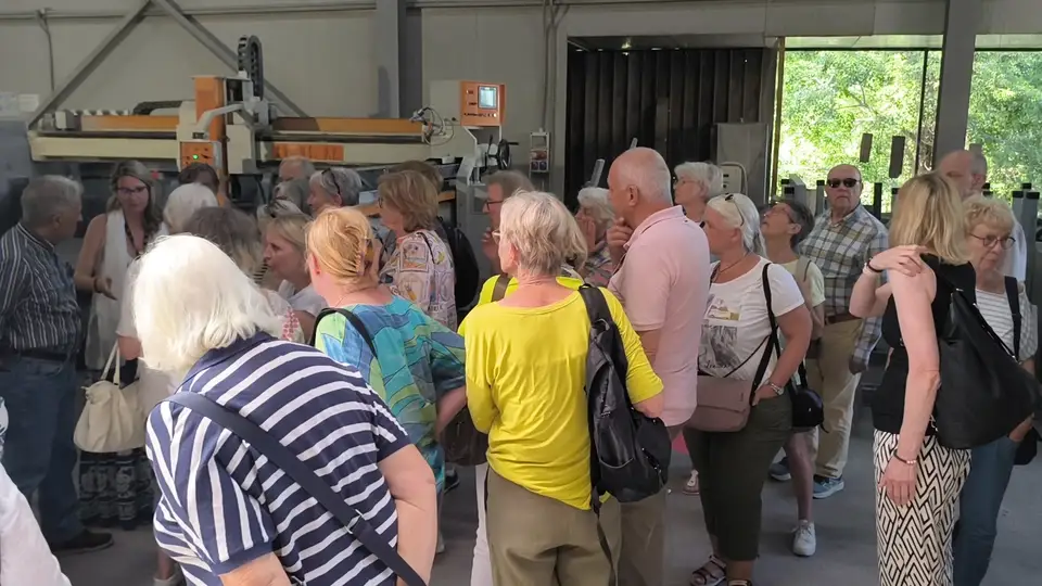 A stop in the production area to discover how lava stone is worked. Group of visitors in the stone processing area beside the machinery