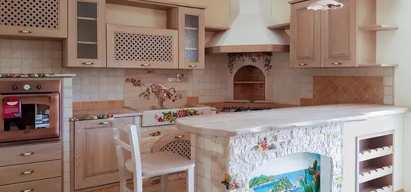 Apulia faux masonry kitchen with light wooden cabinet doors and a peninsula with a painted panel