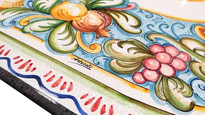 Edge of the Milazzo lava stone table, detail of the colorful floral motifs and red decoration.