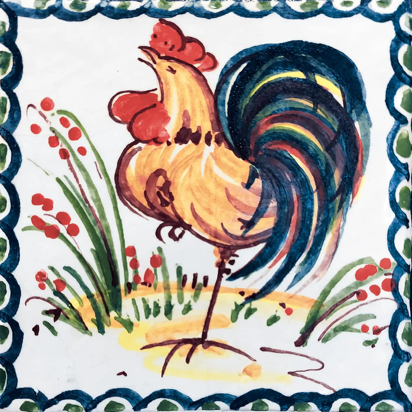 Decorated tile with a yellow rooster with a red comb and blue tail, small flowering stems and a blue border on a white background
