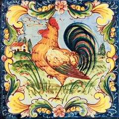 Decorated tile with a rooster in a rural landscape, surrounded by a blue frame with yellow and green leaves and small pink flowers